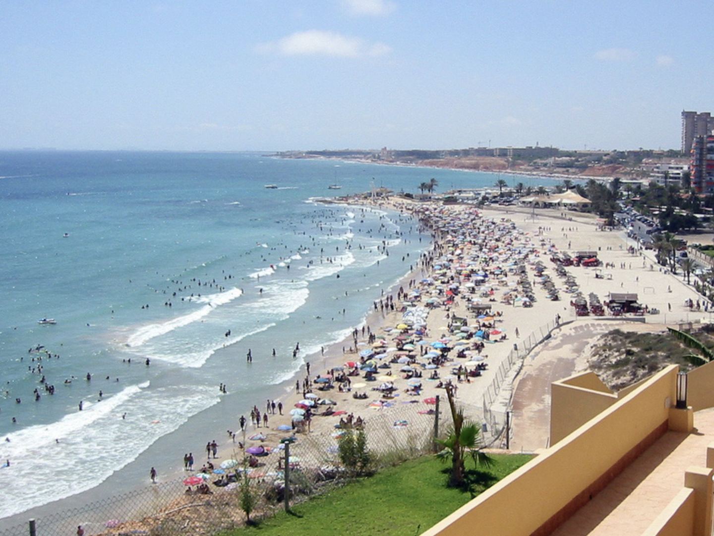 A long sandy beach on the southern Costa Blanca, with bathers and the coastal town behind