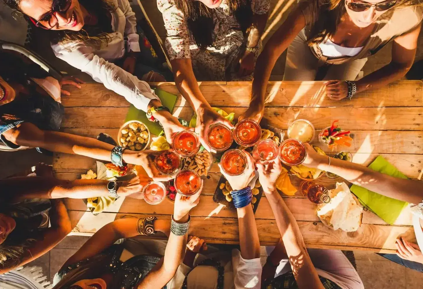 Friends seen from above, raising glasses over a wooden table