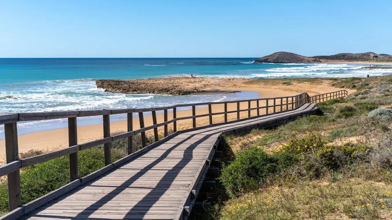 Wooden boardwalk leading down to a sandy beach and rocky point on the Costa Blanca